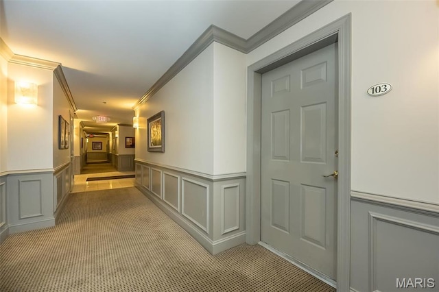 hall with ornamental molding, a decorative wall, and a wainscoted wall