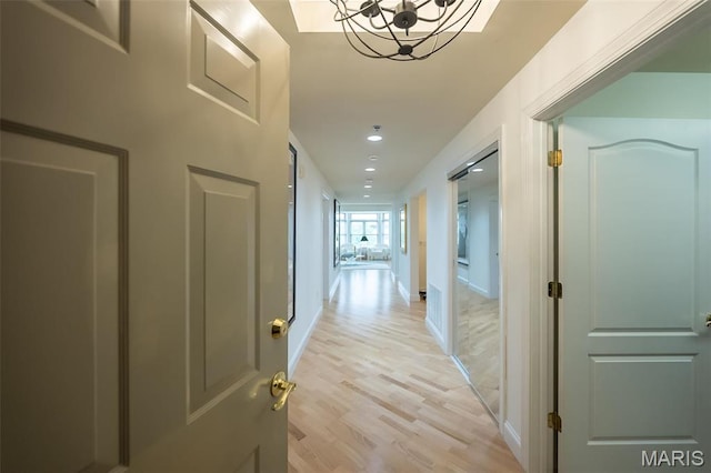 corridor with light wood-style floors, a chandelier, recessed lighting, and baseboards