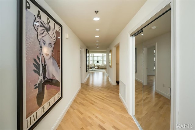 corridor featuring light wood-style flooring, recessed lighting, and baseboards