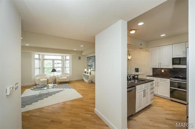 kitchen featuring appliances with stainless steel finishes, open floor plan, dark countertops, white cabinetry, and recessed lighting
