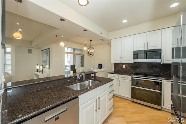 kitchen featuring a sink, stainless steel appliances, decorative backsplash, dark stone countertops, and pendant lighting