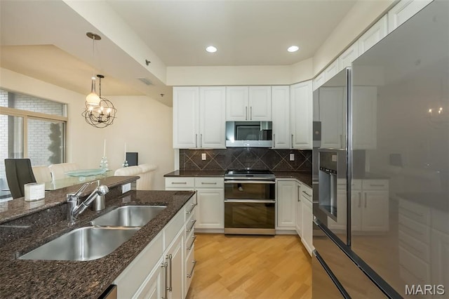 kitchen with appliances with stainless steel finishes, a sink, white cabinetry, and recessed lighting