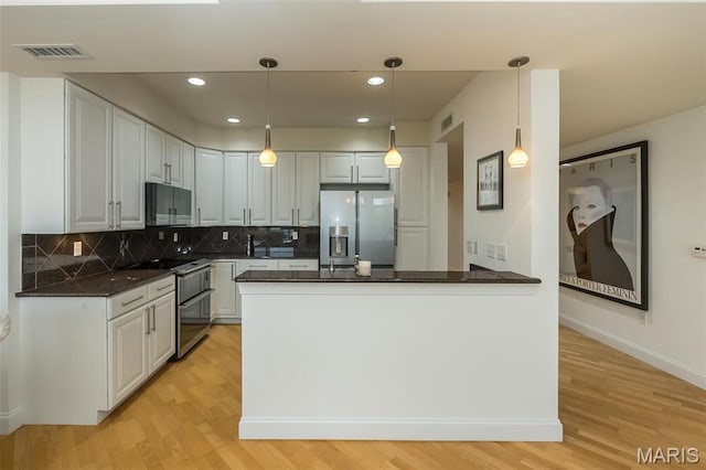 kitchen with appliances with stainless steel finishes, light wood finished floors, a peninsula, decorative backsplash, and recessed lighting