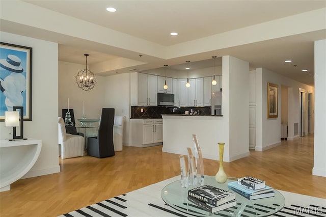 kitchen with appliances with stainless steel finishes, light wood finished floors, tasteful backsplash, a chandelier, and hanging light fixtures