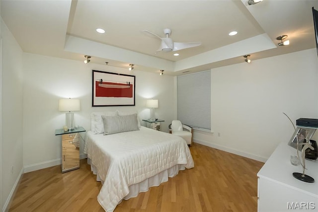bedroom with a raised ceiling, baseboards, light wood finished floors, and recessed lighting