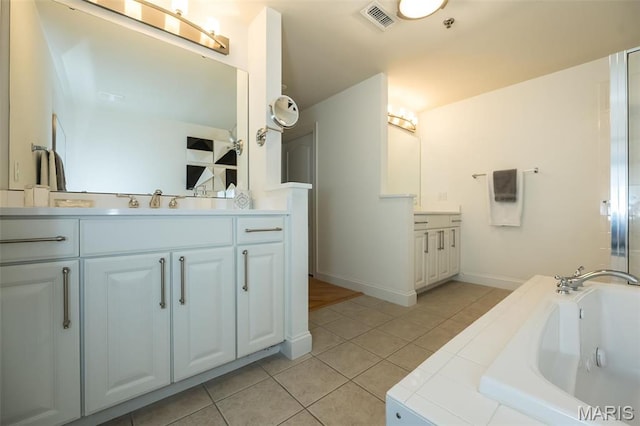 bathroom with tile patterned floors, a garden tub, two vanities, and baseboards