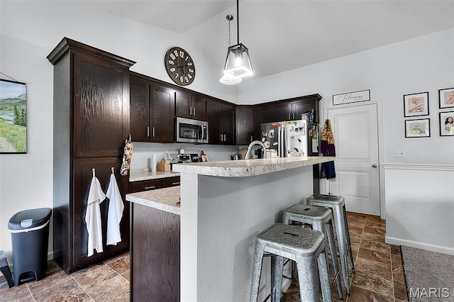 111 Hammond Dr, Herculaneum, MO 63048 - kitchen featuring appliances with stainless steel finishes, stone tile floors, a breakfast bar, light countertops, and dark brown cabinetry