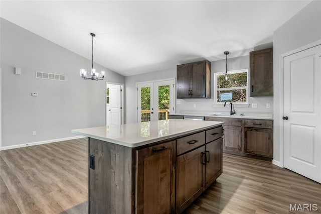 943 Stone Gate Dr, De Soto, MO 63020 - kitchen with a sink, vaulted ceiling, wood finished floors, light countertops, and decorative light fixtures