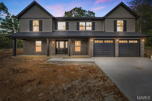 943 Stone Gate Dr, De Soto, MO 63020 - view of front of house featuring an attached garage, concrete driveway, covered porch, and roof with shingles