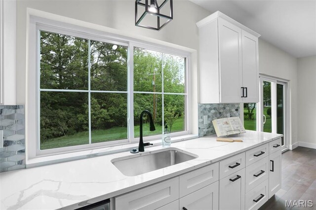 683 Bellerive Estates Dr, Saint Louis, MO 63141 - kitchen with a sink, tasteful backsplash, white cabinets, light stone counters, and baseboards