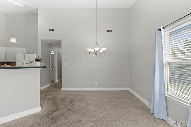 84 Timber Creek Dr Unit 8D, Ofallon, MO 63368 - unfurnished dining area featuring light carpet, a chandelier, a towering ceiling, and baseboards