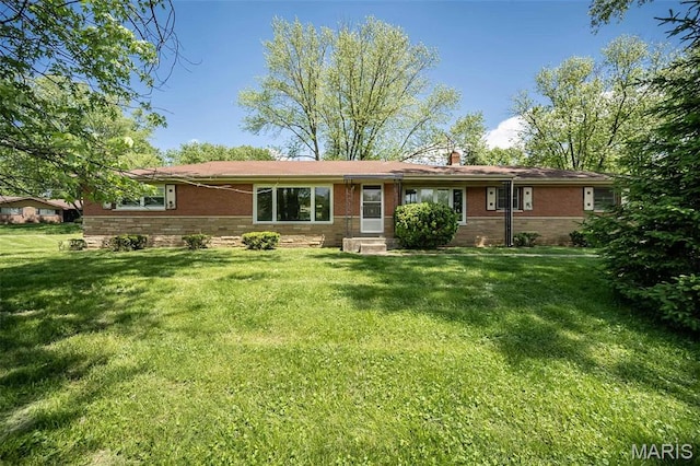 view of front of house featuring a front yard, a chimney, and brick siding
