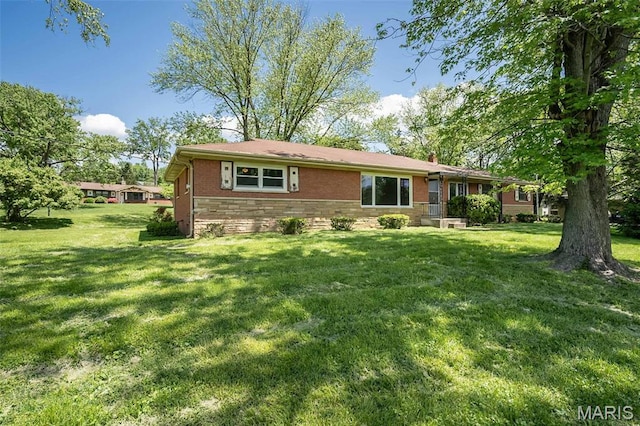 view of front of home featuring brick siding, a chimney, and a front lawn