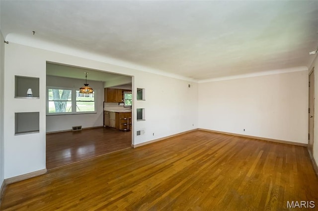 unfurnished living room with wood finished floors and baseboards