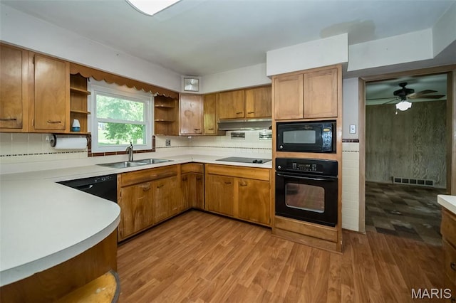 kitchen with black appliances, open shelves, a sink, under cabinet range hood, and decorative backsplash