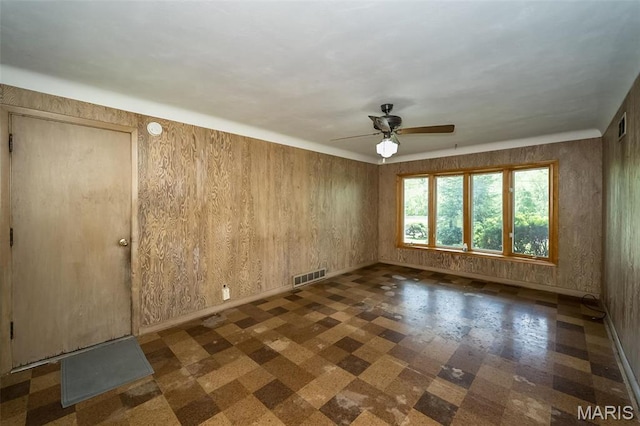 empty room featuring tile patterned floors, a ceiling fan, and baseboards