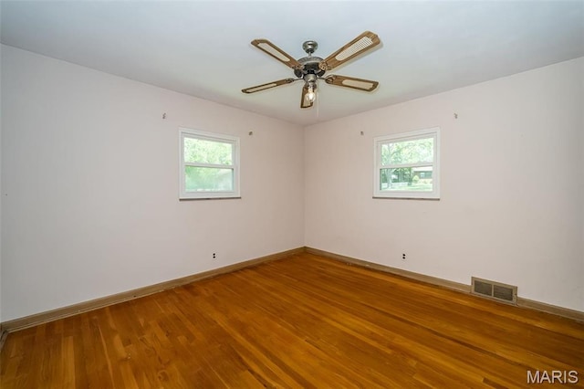 empty room with healthy amount of natural light, baseboards, and wood finished floors