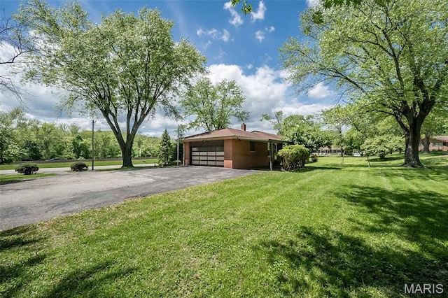 view of front of property featuring asphalt driveway, a garage, and a front yard