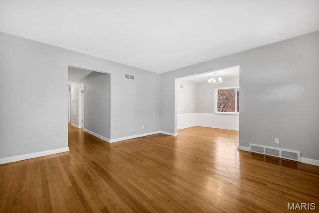 7114 Clayton Rd, Saint Louis, MO 63117 - spare room featuring a chandelier, wood finished floors, and baseboards