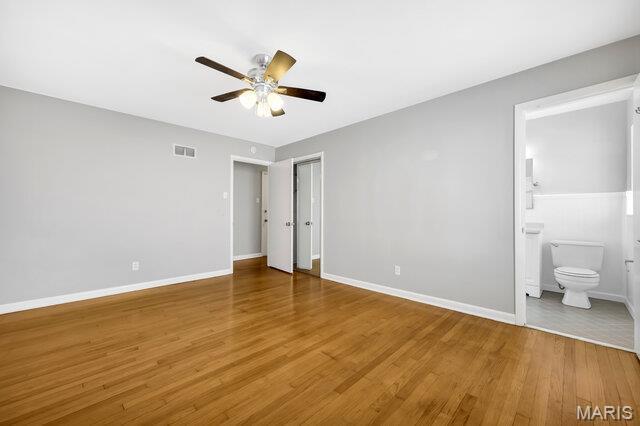 7114 Clayton Rd, Saint Louis, MO 63117 - unfurnished bedroom with wood finished floors, baseboards, ensuite bathroom, and a ceiling fan