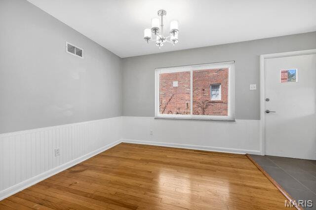 7114 Clayton Rd, Saint Louis, MO 63117 - unfurnished dining area with a chandelier and wood finished floors