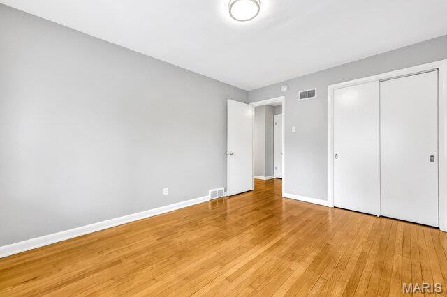 7114 Clayton Rd, Saint Louis, MO 63117 - unfurnished bedroom with light wood-style flooring, baseboards, and a closet