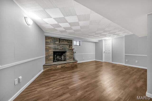 7114 Clayton Rd, Saint Louis, MO 63117 - unfurnished living room with a stone fireplace, wood finished floors, and baseboards