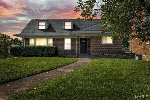 7114 Clayton Rd, Saint Louis, MO 63117 - view of front facade with a front lawn, brick siding, and roof with shingles