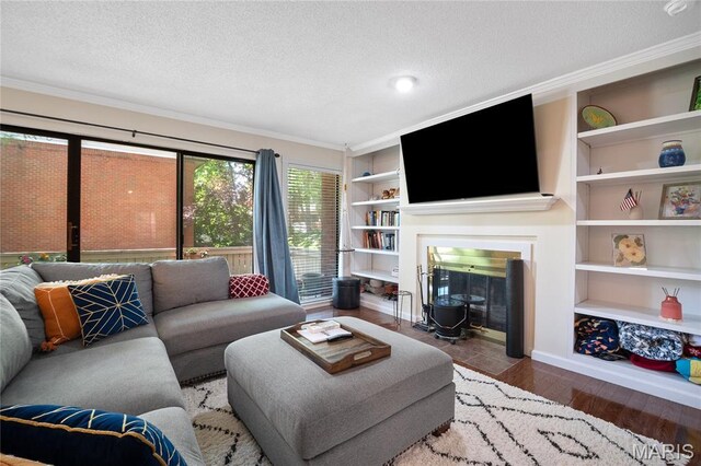 5567 Waterman Blvd Unit D, Saint Louis, MO 63112 - living area with built in shelves, a textured ceiling, ornamental molding, a fireplace with flush hearth, and wood finished floors