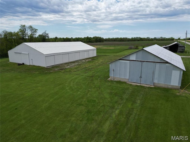 view of grassy yard featuring a pole building, an outbuilding, and a view of rural / pastoral area