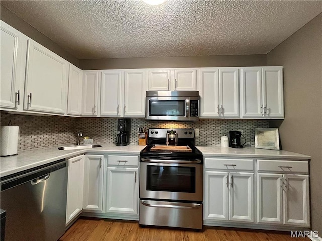 9169 N Swan Cir, Brentwood, MO 63144 - kitchen featuring appliances with stainless steel finishes, a sink, light countertops, a textured ceiling, and decorative backsplash