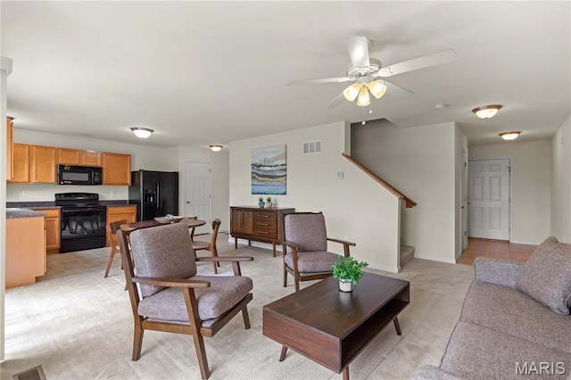 living room with a ceiling fan, light carpet, stairway, and baseboards