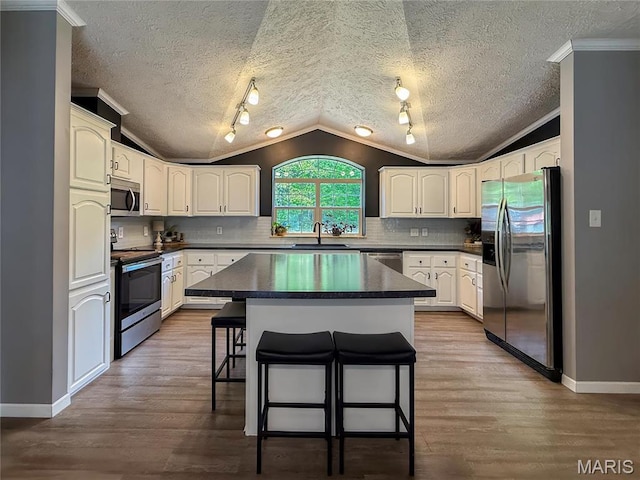 4311 Lakeview Dr, Hillsboro, MO 63050 - kitchen featuring appliances with stainless steel finishes, lofted ceiling, dark countertops, a breakfast bar area, and crown molding