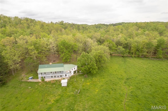aerial view of property and surrounding area featuring a heavily wooded area