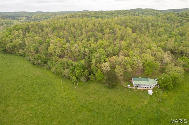 aerial view of property and surrounding area featuring a heavily wooded area