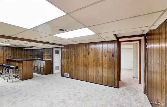 indoor bar with wooden walls, carpet flooring, and a paneled ceiling