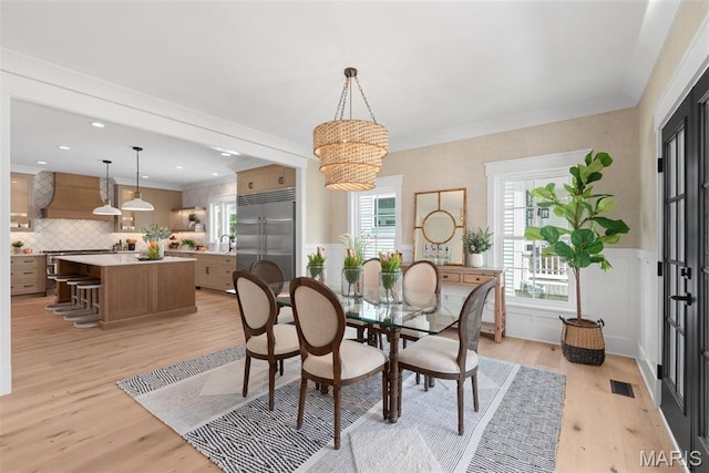 601 Foote Ave, Webster Groves, MO 63119 - dining area featuring light wood-type flooring, a wainscoted wall, and crown molding