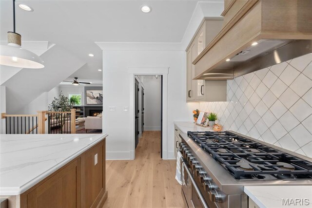 601 Foote Ave, Webster Groves, MO 63119 - kitchen with custom range hood, light wood-style flooring, a ceiling fan, a warm lit fireplace, and light stone counters