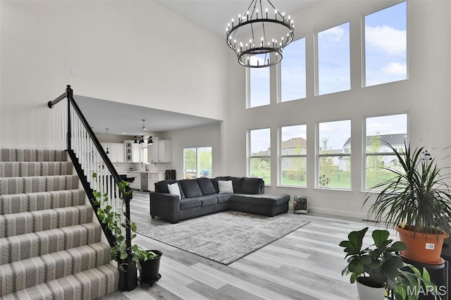 112 Westhaven View Dr, Wentzville, MO 63385 - living room featuring light wood-style flooring, stairway, a towering ceiling, a chandelier, and baseboards