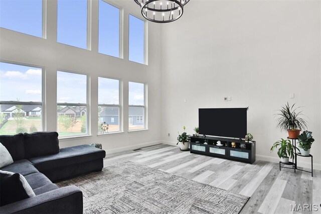 112 Westhaven View Dr, Wentzville, MO 63385 - living area featuring healthy amount of natural light, a chandelier, wood finished floors, baseboards, and a towering ceiling