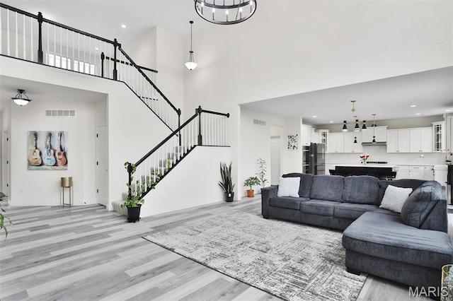112 Westhaven View Dr, Wentzville, MO 63385 - living room featuring a towering ceiling, light wood finished floors, recessed lighting, stairs, and baseboards