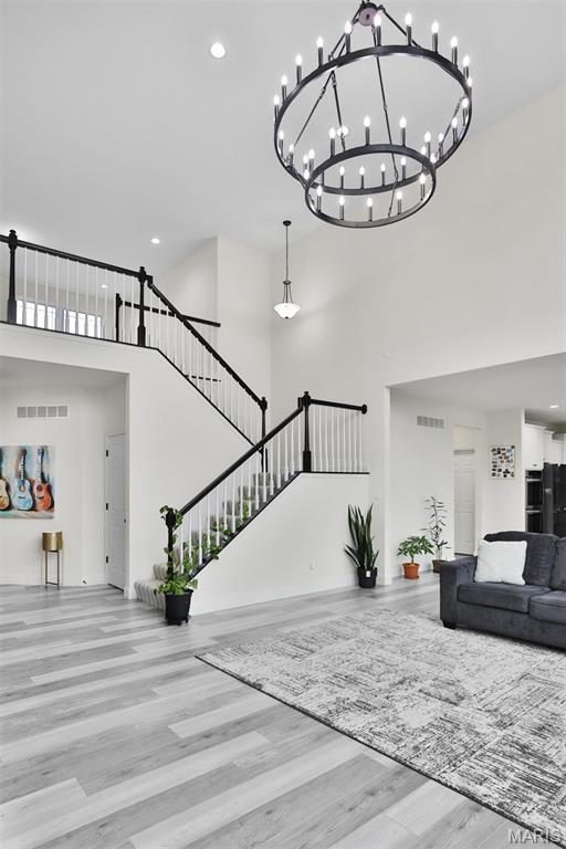 112 Westhaven View Dr, Wentzville, MO 63385 - living room with a towering ceiling, wood finished floors, stairway, recessed lighting, and a chandelier