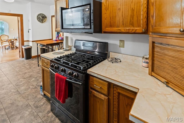 113 Orchard Dr, Belleville, IL 62221 - kitchen with black gas range oven, light countertops, brown cabinetry, and light tile patterned flooring