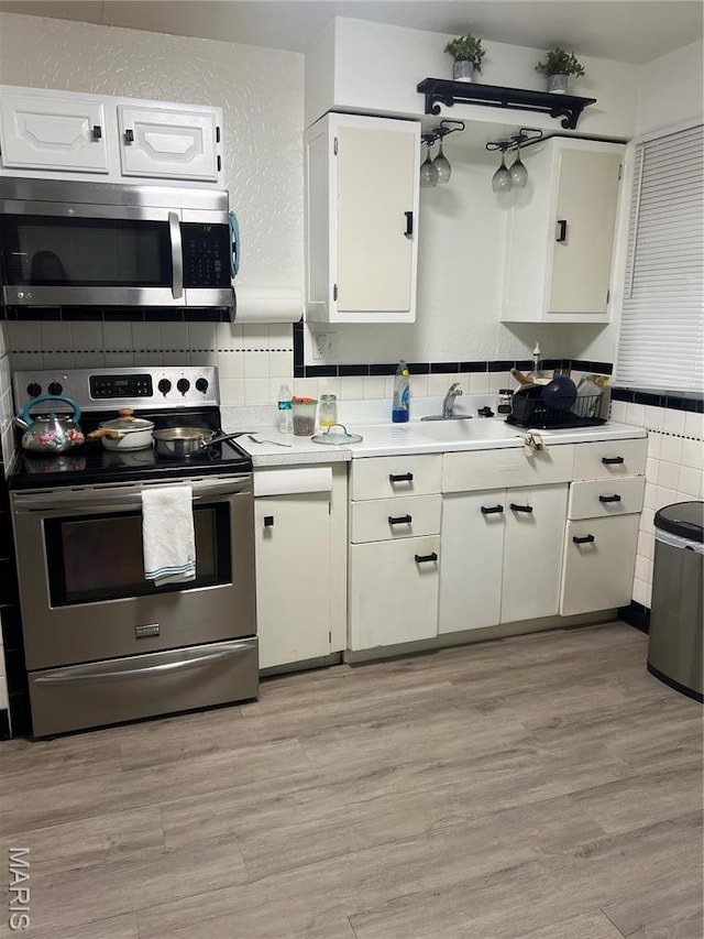 7401 Pleaseway Dr, Saint Louis, MO 63136 - kitchen featuring appliances with stainless steel finishes, a sink, light countertops, and white cabinetry