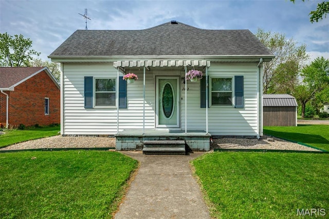 view of front of home with roof with shingles and a front yard