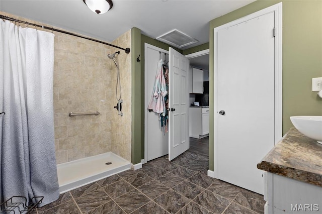bathroom featuring a tile shower and vanity
