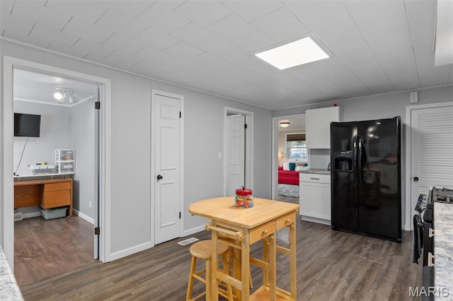 kitchen with black fridge, dark wood finished floors, stainless steel gas range, and white cabinetry