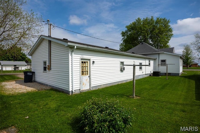 view of side of property featuring a yard and central AC