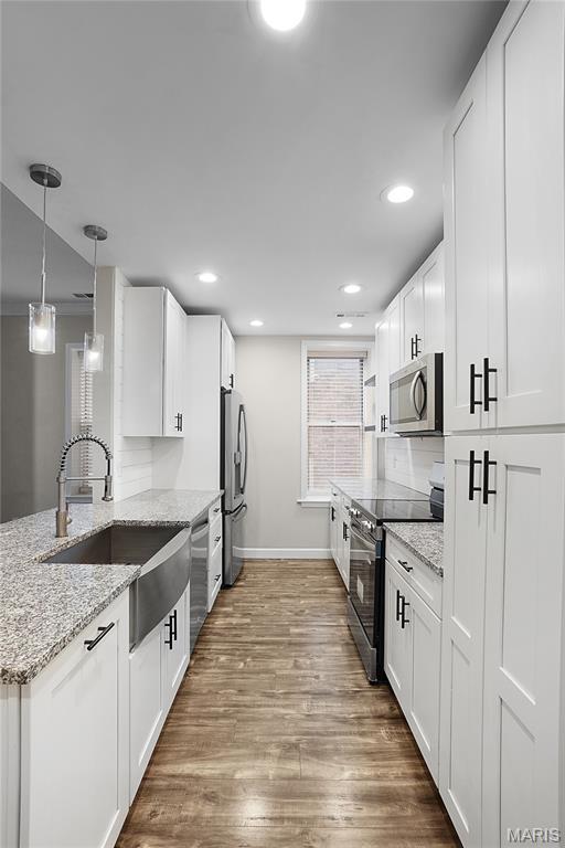 4250 Lindell Blvd Unit A, Saint Louis, MO 63108 - kitchen with appliances with stainless steel finishes, a sink, baseboards, wood finished floors, and white cabinets