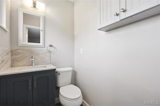 bathroom featuring toilet, vanity, and baseboards